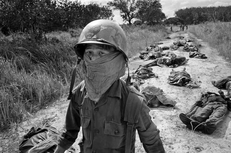 A Vietnamese medic wears a face mask to keep out the smell as he passes the bodies of U.S. and Vietnamese soildiers killed fighting the Viet Cong, November 1965.