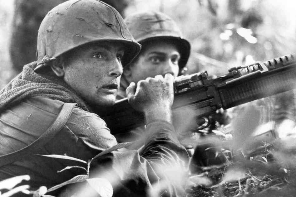 U.S. machine gunner Spc. 4 James R. Pointer (left) and Pfc. Herald Spracklen of Effingham, Ill., peer from the brush of an overgrown rubber plantation during a firefight, December 1967.