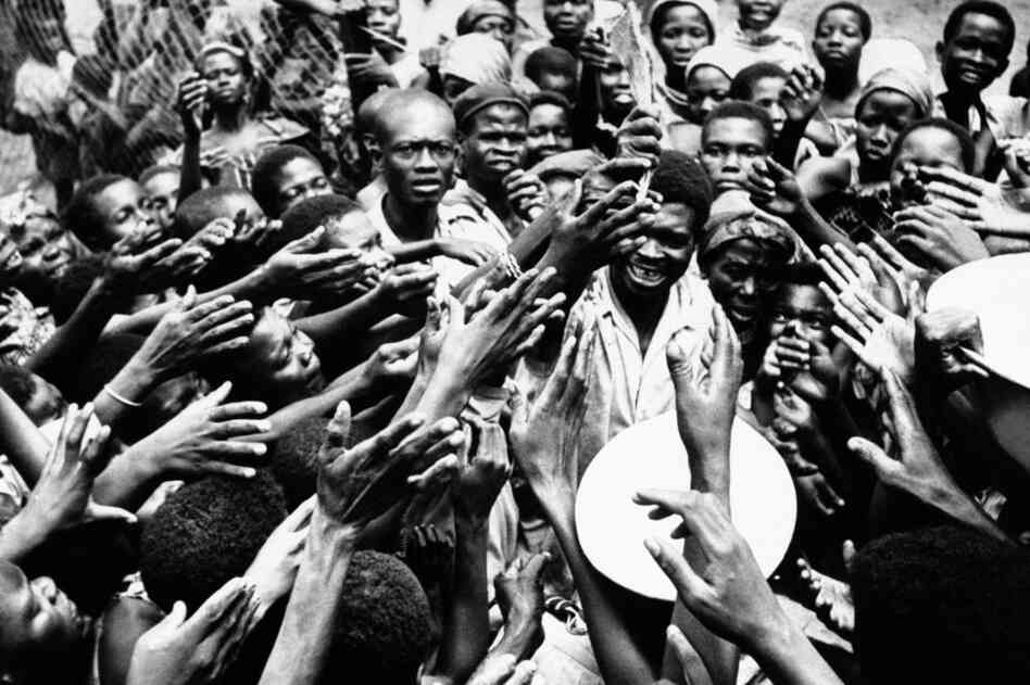 Scores of eager hands reach toward the Congolese official who distributes small rations of dried fish and palm oil to people at the hospital in Miabi, South Kasai, Congo, January 1961.