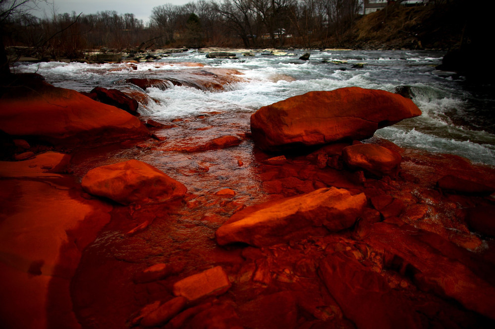 Rocks on the shore of the Lackawanna River in Duryea, Pa., are discolored by iron oxide and sulfur compounds — pollutants left behind by past coal mining in the state.