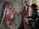 Conservator Angelyn Bass cleans and stabilizes the surface of a wall of a Mayan house that dates to the ninth century. The figure of a man who may have been the town scribe appears on the wall to her left. Conservator Angelyn Bass cleans and stabilizes the surface of a wall of a Mayan house that dates to the ninth century. The figure of a man who may have been the town scribe appears on the wall to her left.