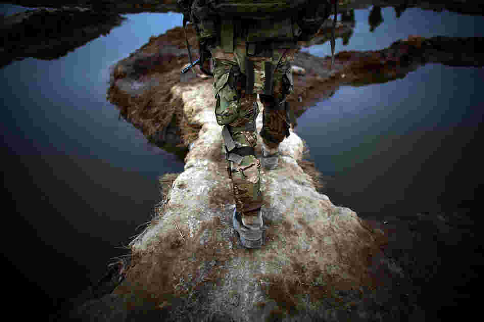 An American soldier walks between puddles while on patrol. U.S. troops based at a combat outpost in the village of Zangabad have nicknamed it "Zangaboom," because roadside bombs are a constant danger.