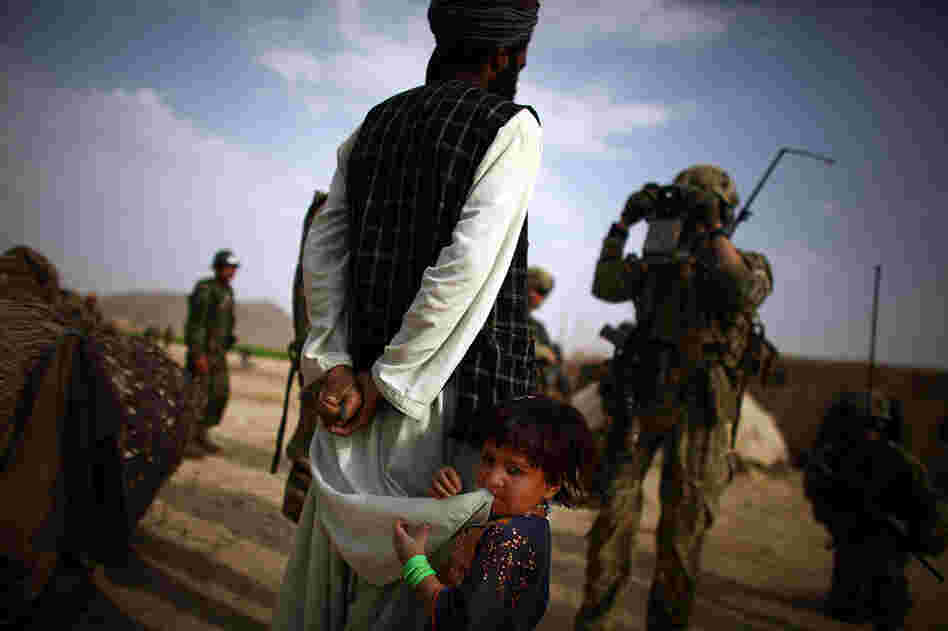A little girl stands behind her father as he is scanned and entered into the database.