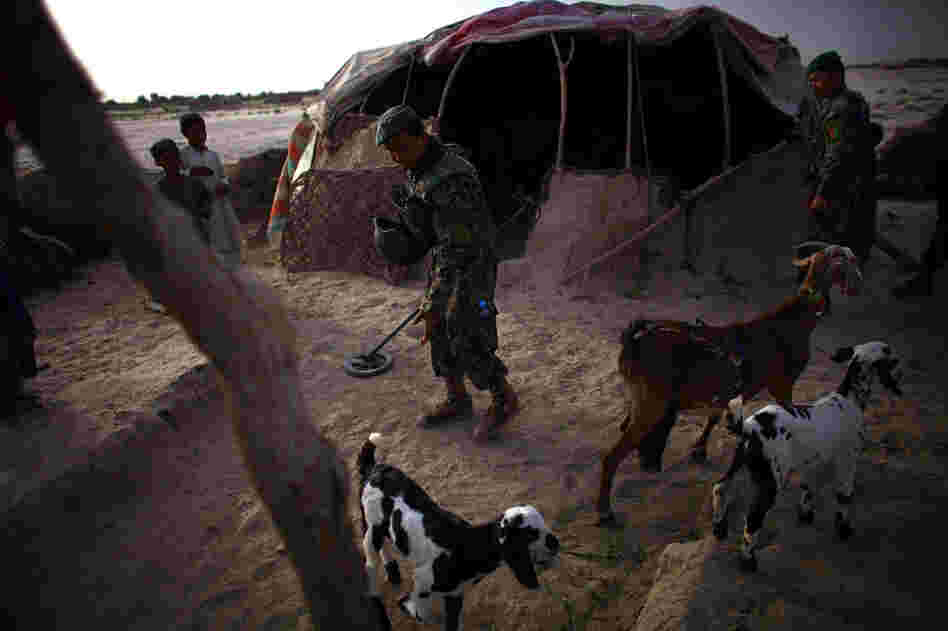 An Afghan soldier uses a metal detector while looking for bomb-making materials at house near Zangabad.