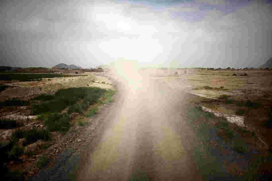 Dust fills the air in the wake of a U.S. Army vehicle as it rumbles down a gravel road in southern Afghanistan.