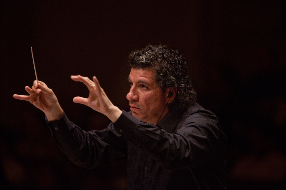 Like the other four conductors in Ives' massive symphony, music director Giancarlo Guerrero wears earbuds to hear the click track needed to keep all the musicians playing together.