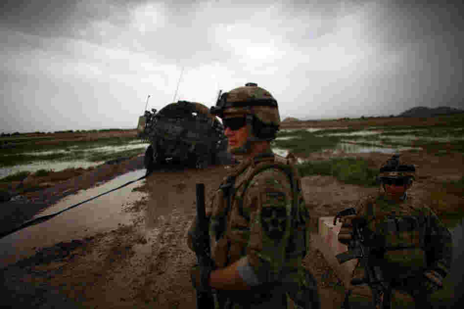 American soldiers keep an eye on the horizon while guarding their armored vehicle, stuck in the mud.
