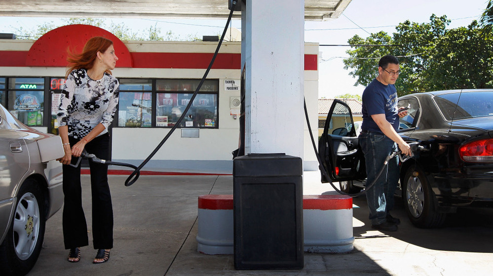 Mayeli Vasallo (left) and Jorge Monte pump gas in Miami in April. The average price of a gallon of gas has dropped 20 cents in the last month, to $3.73.