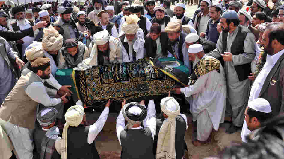 Officials and mourners prepare to place the coffin of Afghanistan High Peace Council and former Taliban leader Arsala Rahmani in a grave earlier today, in Kabul.