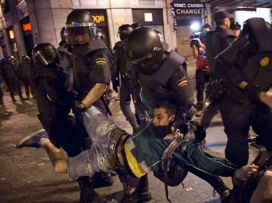 Spanish police officers carry off a demonstrator as he and others are evicted from a square in Madrid on Sunday.
