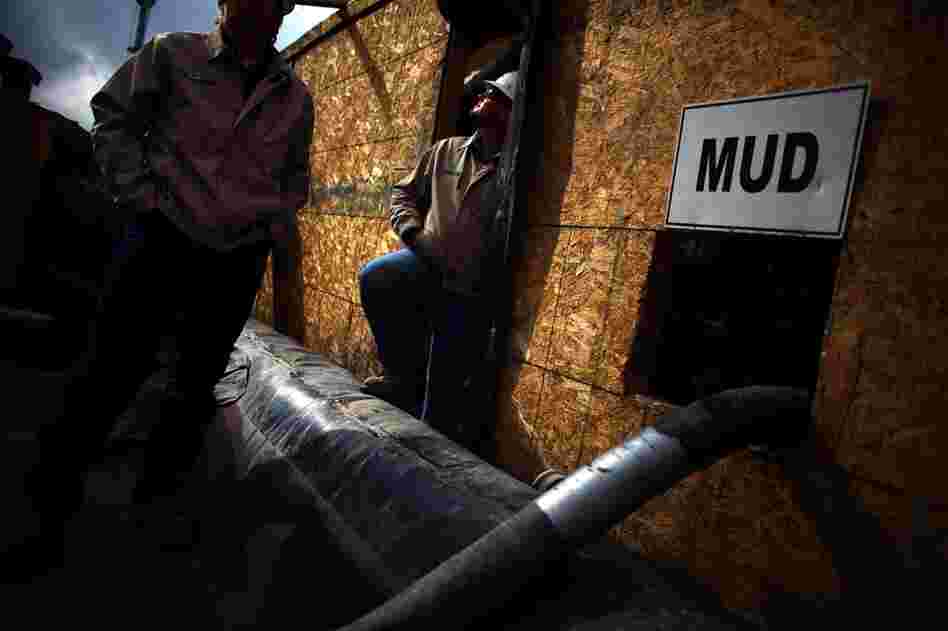 Workers stand outside the pump room where water is separated from drilling mud at one of Chesapeake Energy's water treatment facilities.