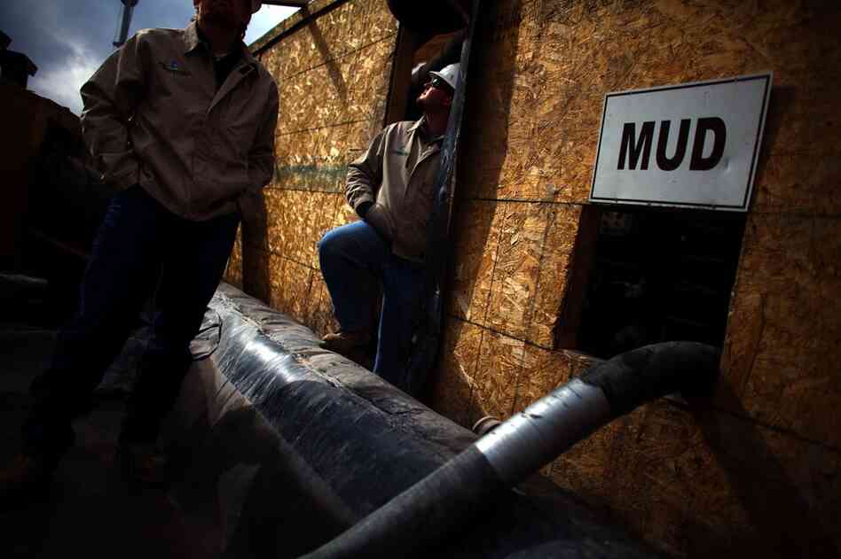 Workers stand outside the pump room where water is separated from drilling mud at one of Chesapeake Energy's water treatment facilities.