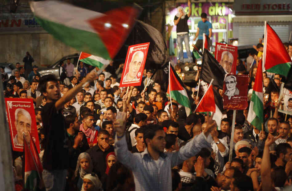 Palestinians hold pictures of prisoners and Palestinian flags as they celebrate the end of a prisoners' hunger strike in Israeli jails, in the West Bank city of Ramallah on Monday.