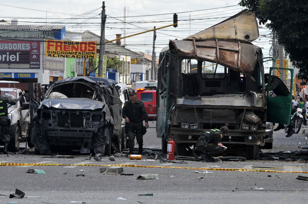 Police officers inspect the remains of vehicles on Tuesday after an explosion ripped through a crowded area of Bogotá injuring at least 10 people according to the mayor's office.