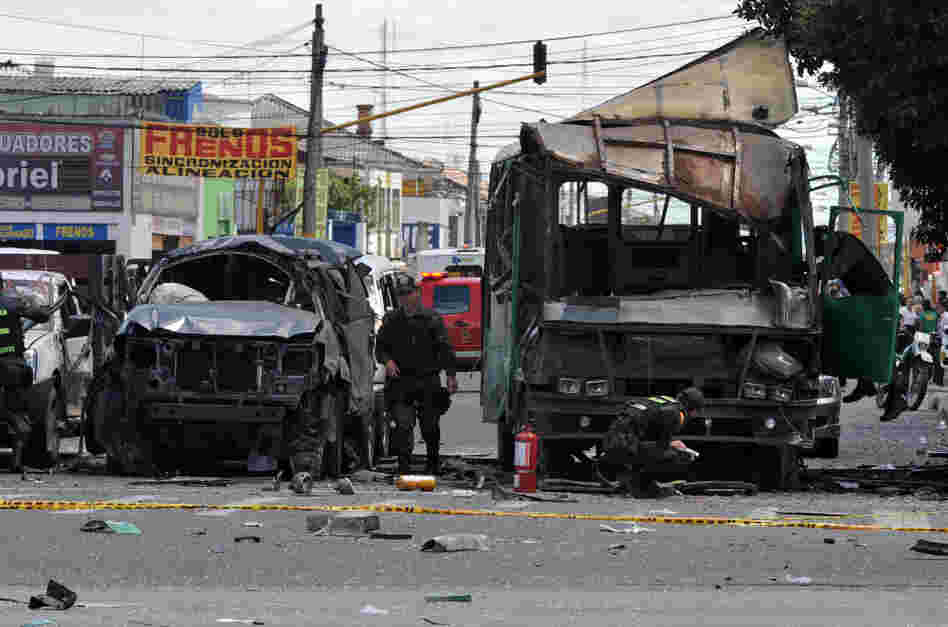 Police officers inspect the remains of vehicles on Tuesday after an explosion ripped through a crowded area of Bogotá injuring at least 10 people according to the mayor's office.