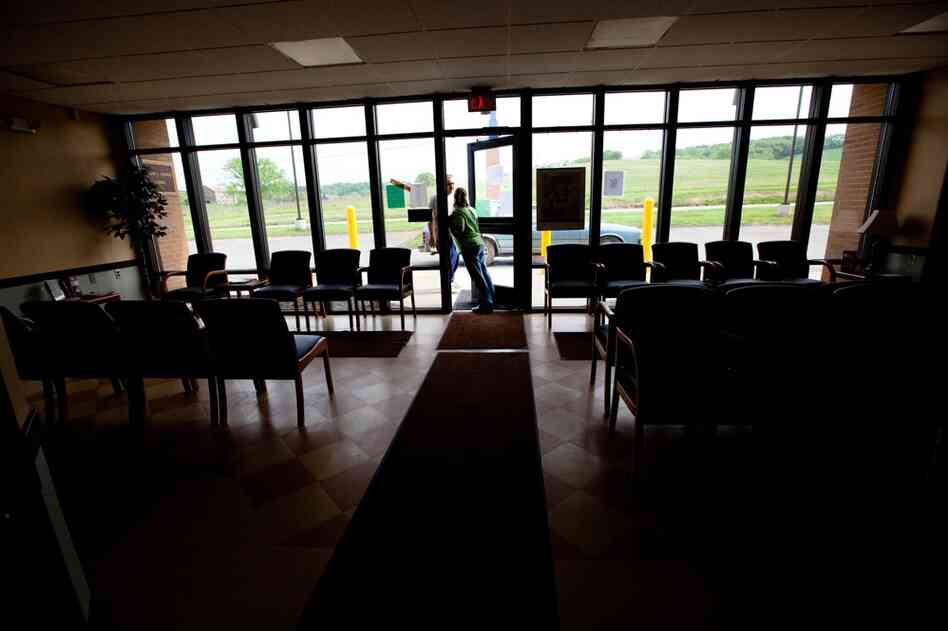 Receptionist Thompson talks with a patient in the doorway of the closed clinic.