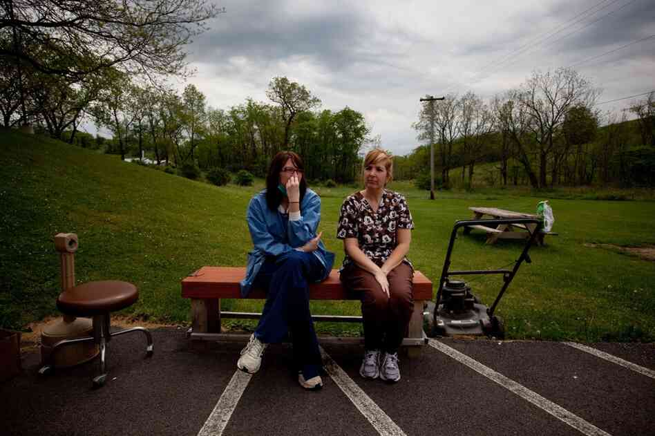 Michelle Salvini (left) and Terri DiCarlo take a break from work outside the Cornerstone Care clinic in Burgettstown, Pa. Mysterious fumes have repeatedly sickened clinic staffers, forcing them to evacuate the building several times.