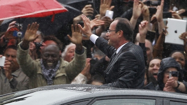 Francois Hollande stands up in his car as he rides up the Champs-Elysees after taking the oath of office as President of France.