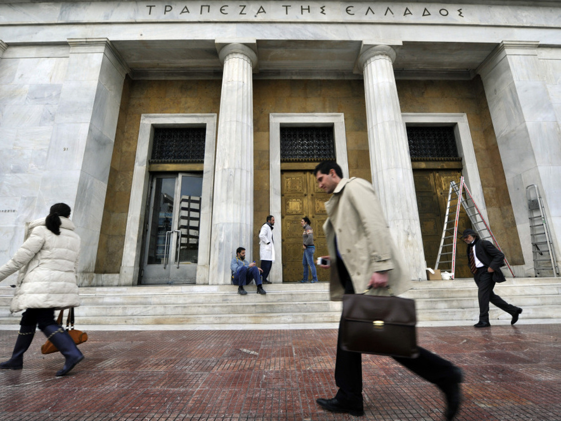 People walk past the Bank of Greece headquarters in Athens.