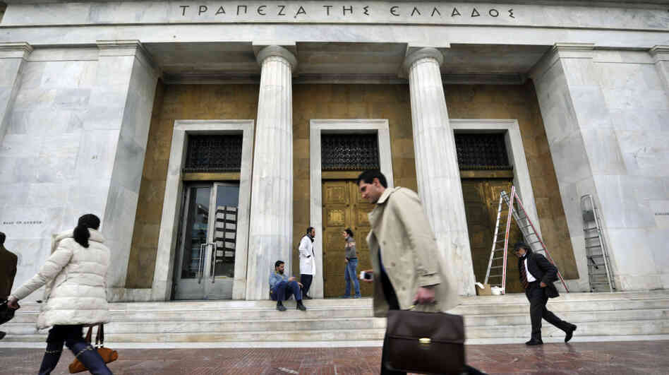 People walk past the Bank of Greece headquarters in Athens.