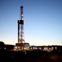 A natural gas drilling rig's lights shimmer in the evening light near Silt, Colo.