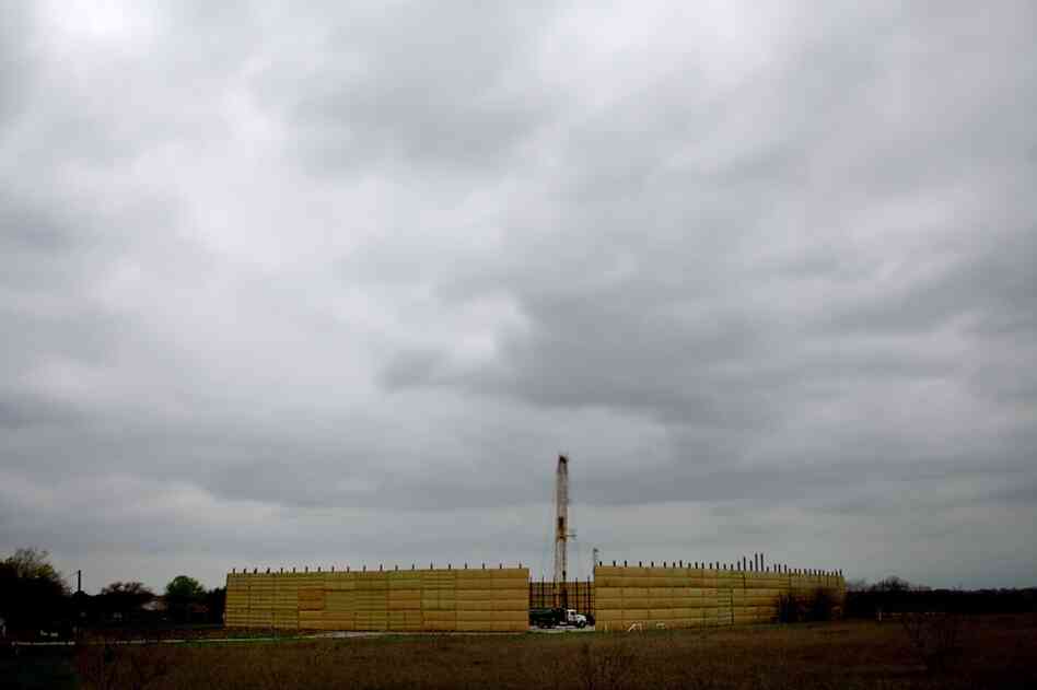 A noise-dampening curtain surrounds a drilling rig near Dish.