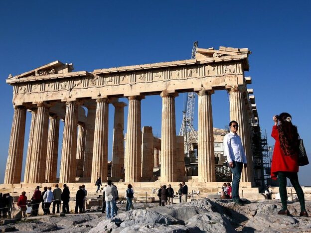 Tourists take pictures in front of the Parthenon Temple in Athens. If Greece leaves the eurozone, it could revert to its own currency, and the price of visiting the country could potentially drop.
