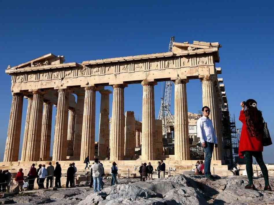 Tourists take pictures in front of the Parthenon Temple in Athens. If Greece leaves the eurozone, it could revert to its own currency, and the price of visiting the country could potentially drop.