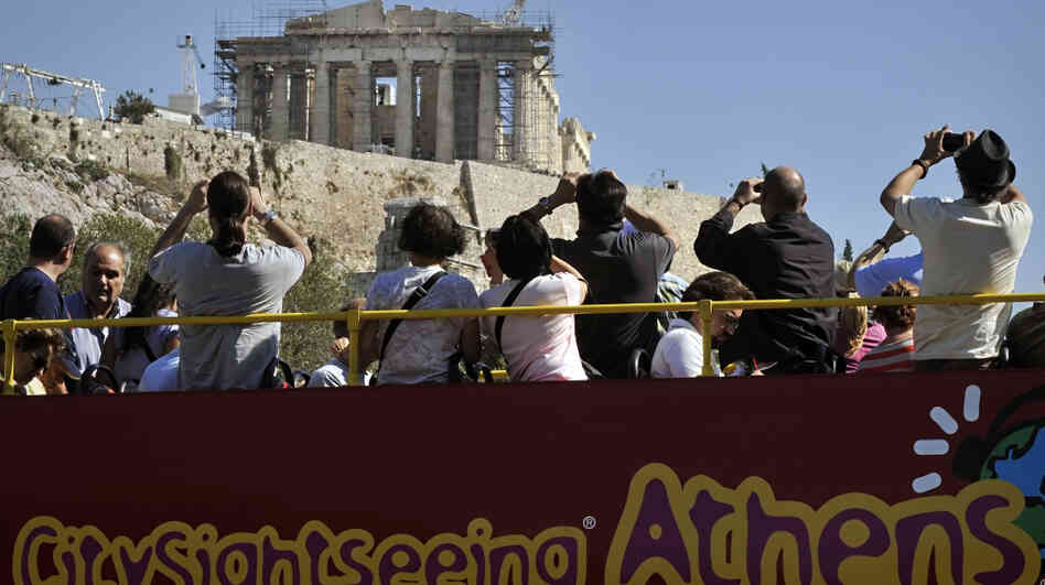 Greece depends heavily on tourism, but the economic crisis is driving away visitors like these ones photographing the Acropolis in Athens from the top of a tour bus last October.