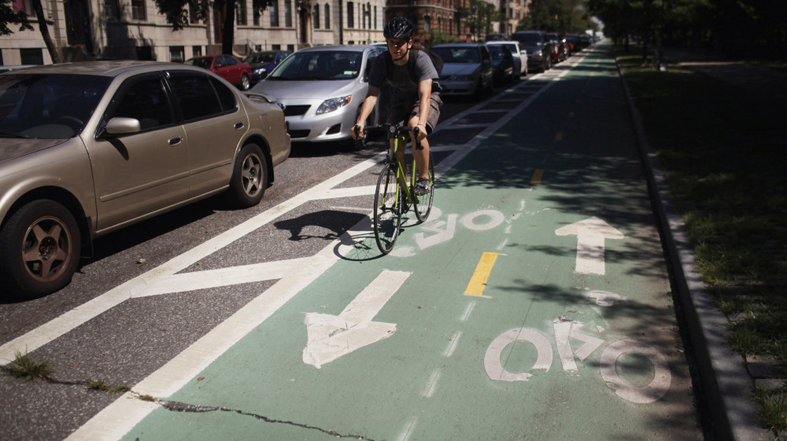 A cyclist rides on a bike lane on Prospect Park West, in the Brooklyn borough of New York City. Bike lanes of this type use parked cars to create a buffer zone from road traffic.