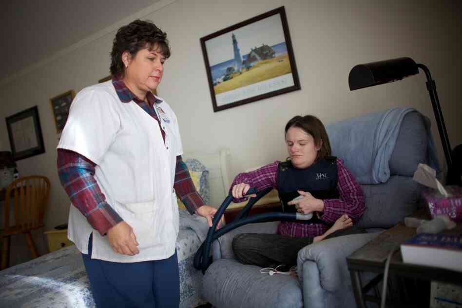 Nurse Vicki Hagen comes over to Beckett's apartment in Cedar Rapids, Iowa, to help fit her with a vibrating vest that helps clear mucous from her lungs twice a day. Studies have shown that, almost always, it costs less to care for someone at home than in a nursing home or hospital.