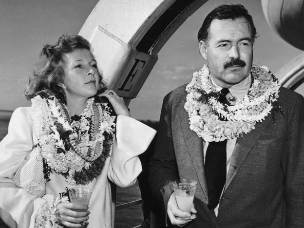 1941: Hemingway and Gellhorn, married in 1940, stand on deck aboard a ship, wearing leis and holding cocktails. They divorced in 1945.