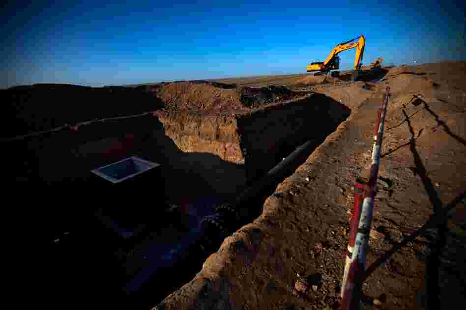 A construction crew works on a section of an underground water pipe and wellhead the Oyu Tolgoi mine is building along the dirt "highway" in South Gobi.