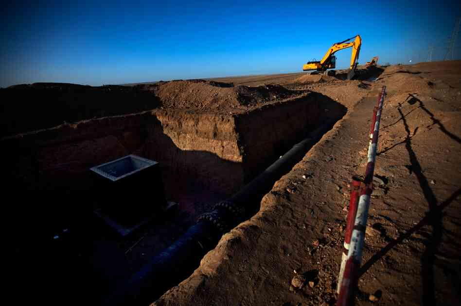A construction crew works on a section of an underground water pipe and wellhead the Oyu Tolgoi mine is building along the dirt "highway" in South Gobi.