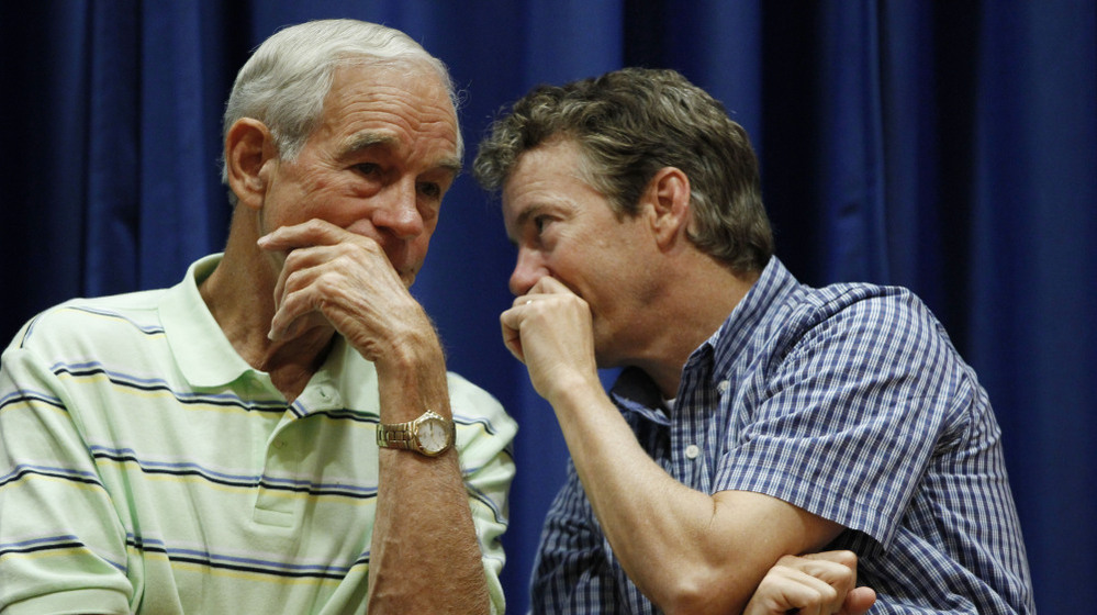 Rep. Ron Paul, R-Texas, and his son, Sen. Rand Paul, R-Ky., talk at a campaign event for the elder Paul in Des Moines, Iowa, last August.