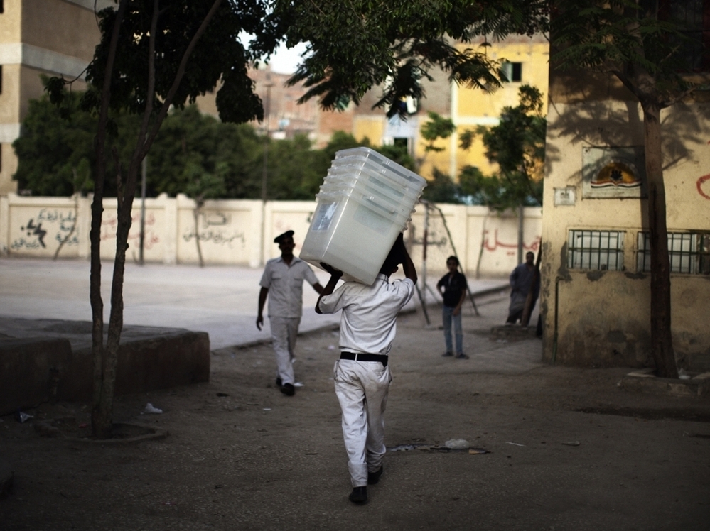 A police officer carries empty ballot boxes to a polling station in Cairo. Turnout is expected to be heavy.