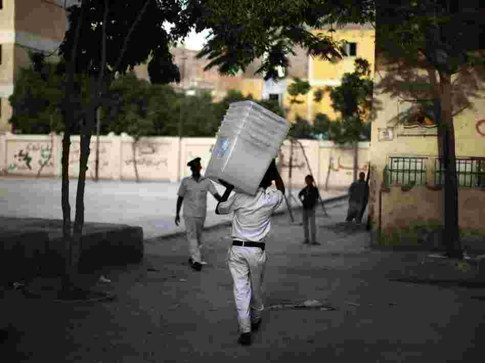 A police officer carries empty ballot boxes to a polling station in Cairo. Turnout is expected to be heavy.