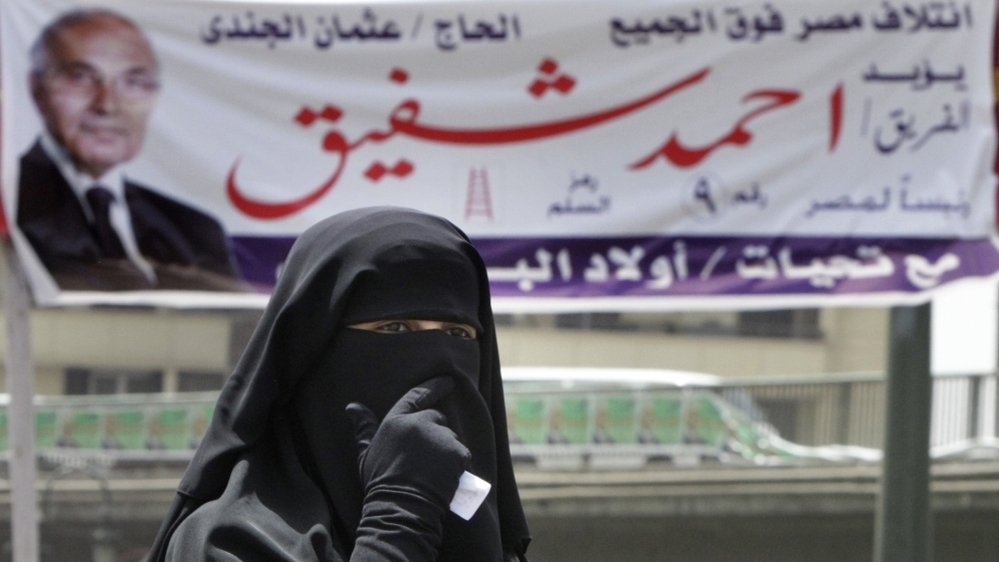 An Egyptian woman walks under a campaign banner in Cairo on Tuesday. Egypt holds its first competitive presidential election on Wednesday and Thursday, with a dozen candidates in the race.