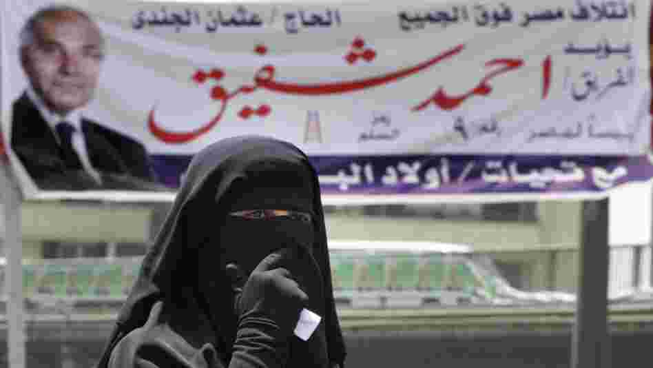 An Egyptian woman walks under a campaign banner in Cairo on Tuesday. Egypt holds its first competitive presidential election on Wednesday and Thursday, with a dozen candidates in the race.