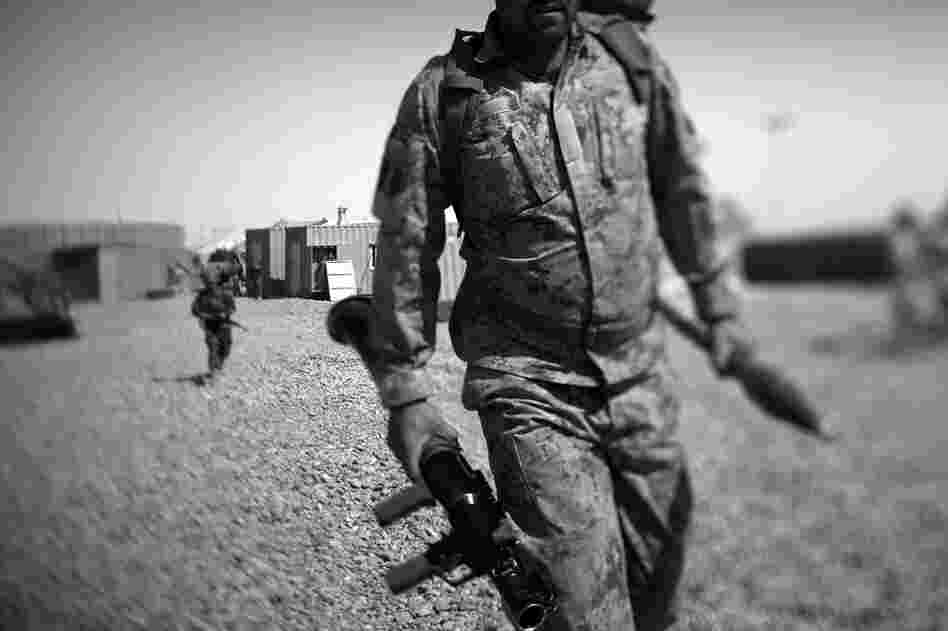 An Afghan policeman carries a rocket-propelled grenade launcher as he leaves for patrol on the outskirts of Marjah, near the Sistani Desert.