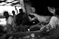 Today, the area is calm. Businessmen, farmers and shop owners gather for tea and conversation at a vegetable stand.
