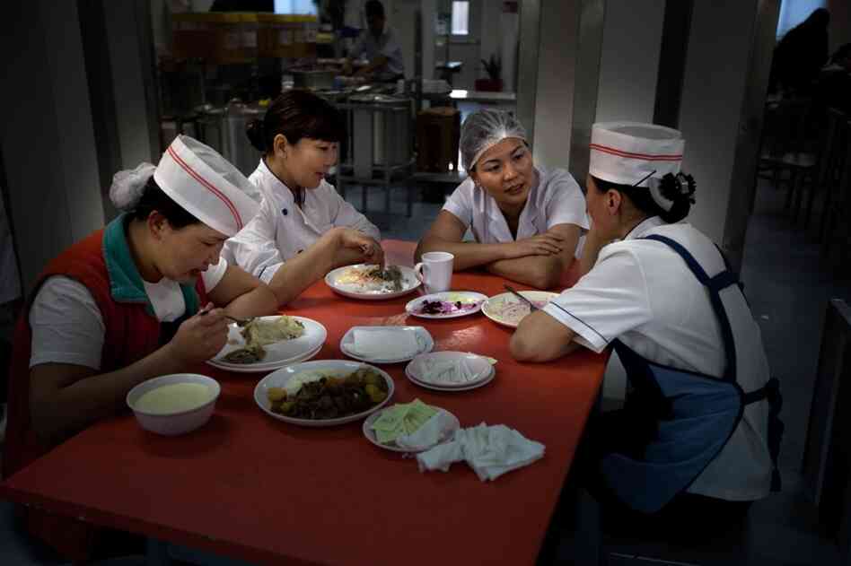 Kitchen workers take a break after the morning rush at the cafeteria, which feeds thousands of workers every day.