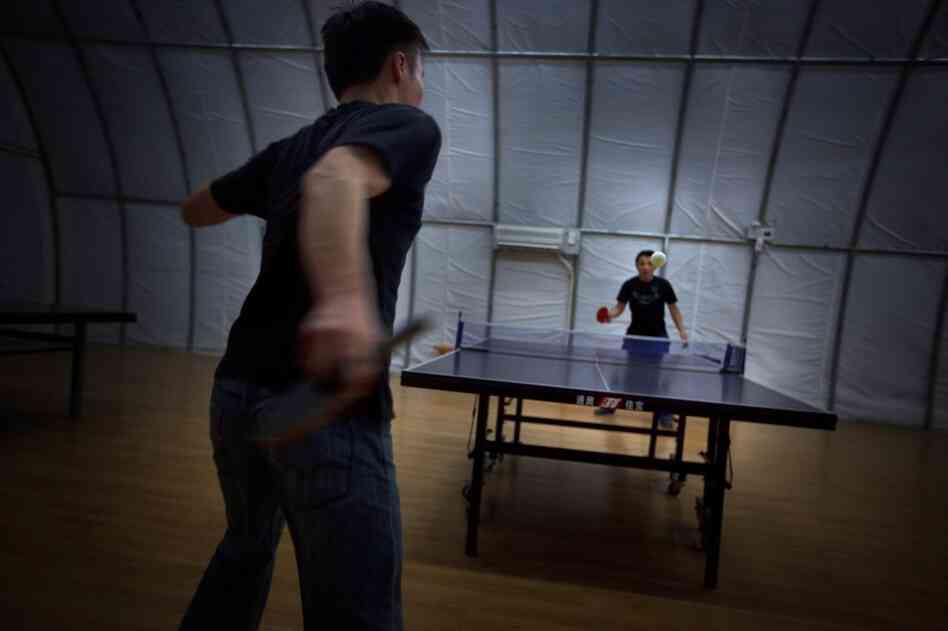 Mine workers play table tennis inside a Quonset hut.
