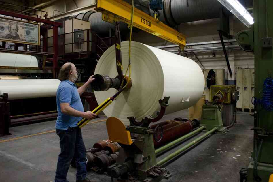 Rewinder operator John Danylieko moves a finished roll of currency paper from the paper machine. The roll will be cut into three narrower rolls before being cut into sheets.
