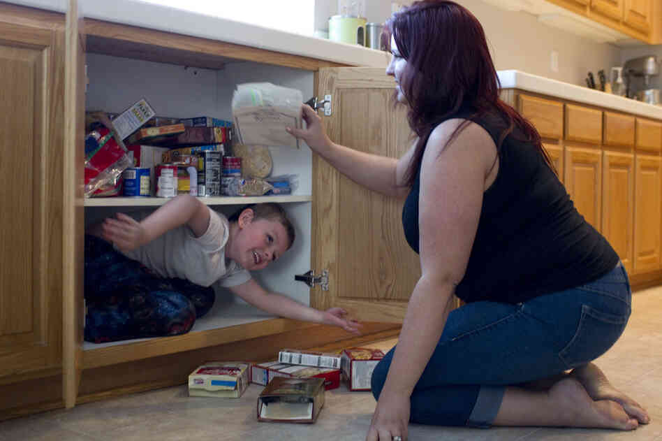 Jaden climbs into a kitchen cabinet, removing the food from the shelves so he can fit. Amber says she can't afford to buy him new shoes or clothes because of her health care expenses.
