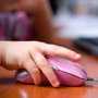 Child's hand on a pink computer mouse.