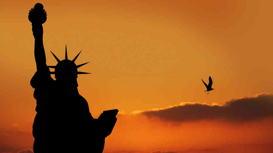 The Statue of Liberty silhouetted by sunset in New York City.