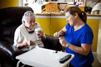 LaDonna talks on the phone with AnnaBelle's granddaughter and LaDonna's sister-in-law, Kelley Hawkins, while helping AnnaBelle with her makeup in her family's living room.