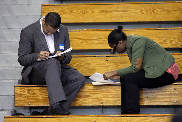 Job seekers fill out applications at a job fair in the Queens borough of New York City earlier this month. Economists say jobs in the middle — in sales, administration and assembly, for example — are being squeezed.