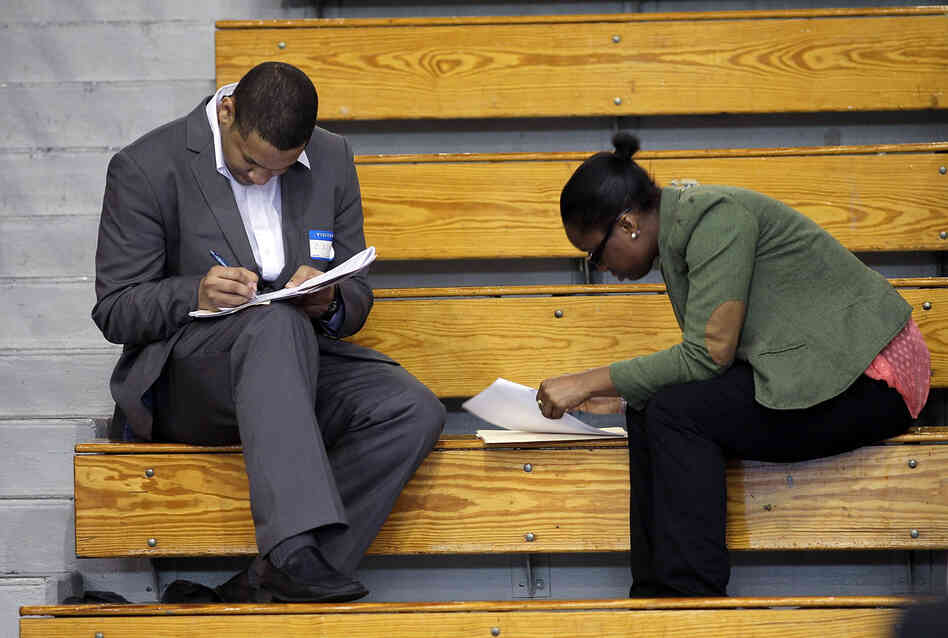Job seekers fill out applications at a job fair in the Queens borough of New York City earlier this month. Economists say jobs in the middle — in sales, administration and assembly, for example — are being squeezed.